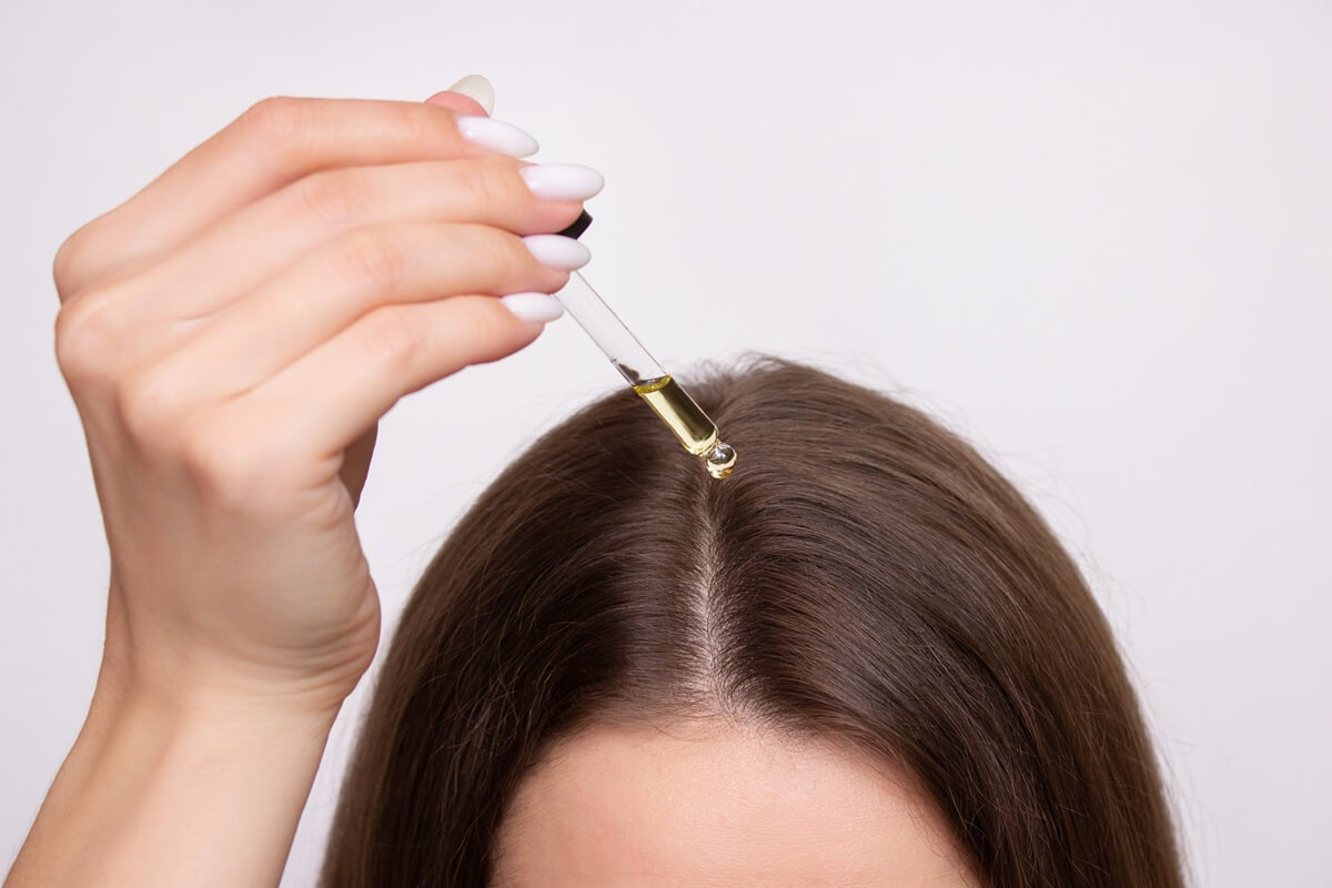 Aplikowanie serum z peptydami na skórę głowy przy pomocy szklanej pipety