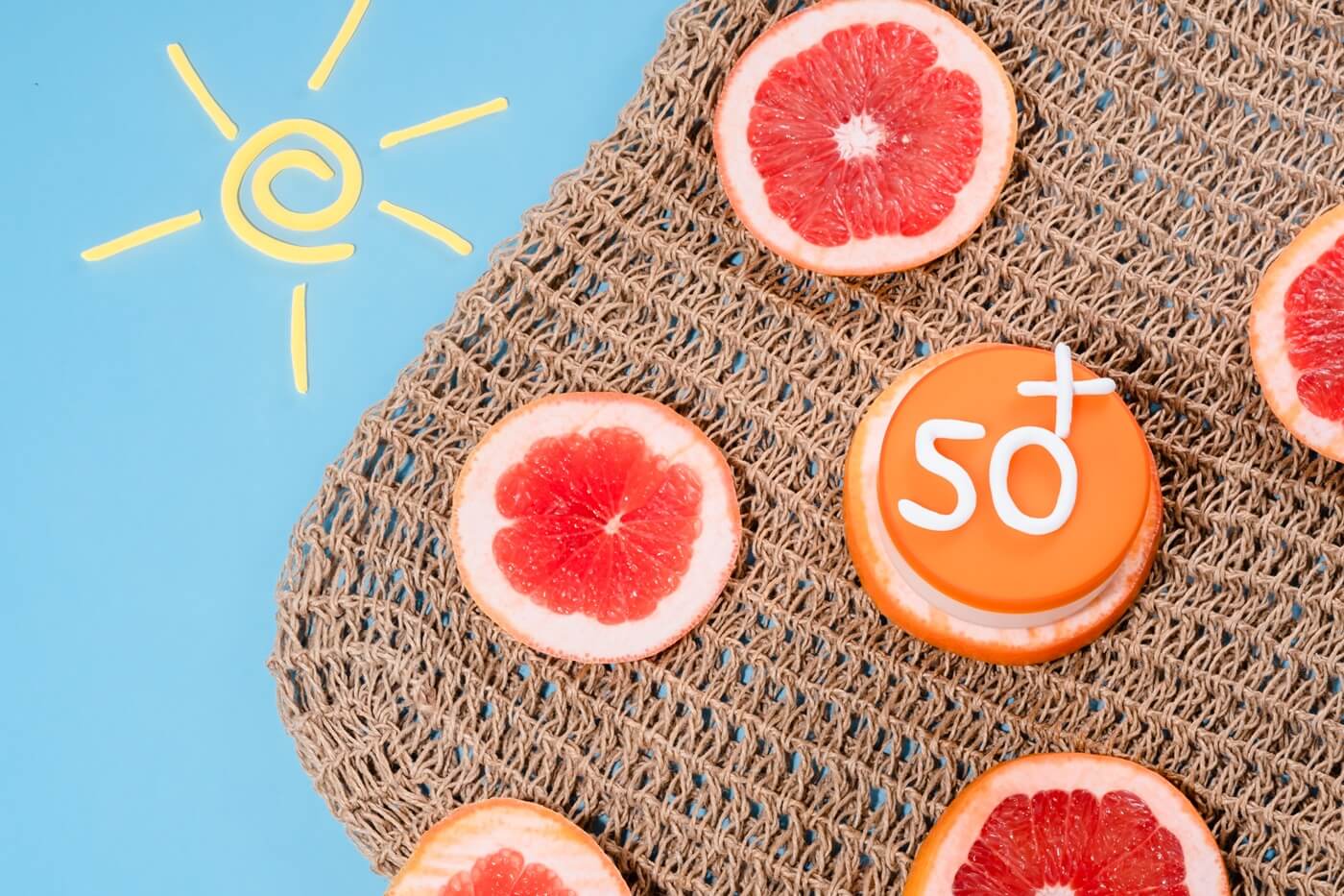 Krem z filtrem SPF 50 i plastry grejpfruta na tle letnich akcesoriów
