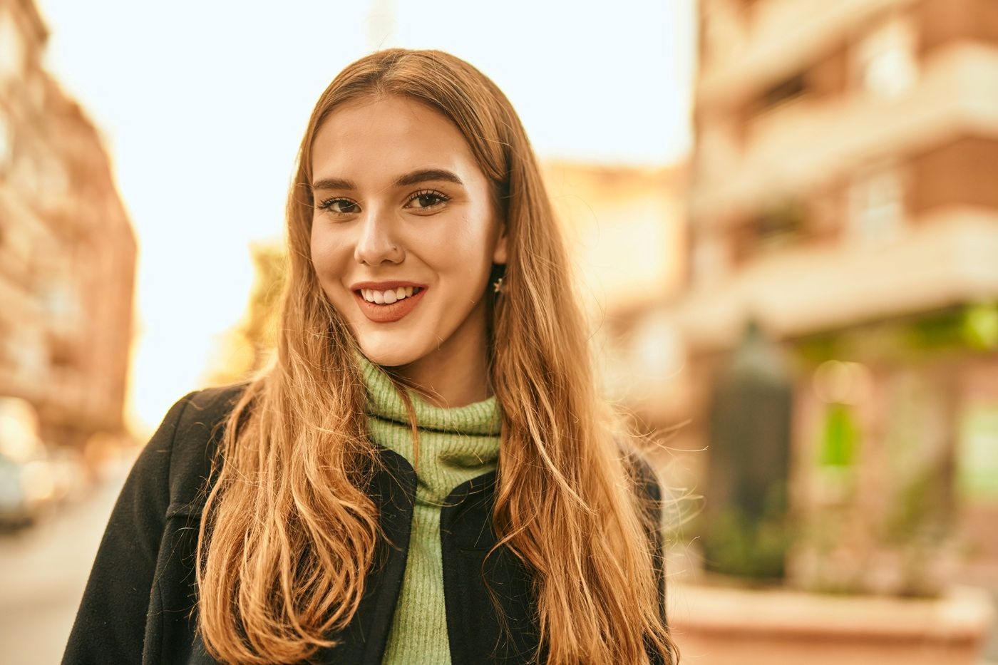 Uśmiechnięta kobieta z długimi włosami w ciepłym, złocistym blondzie.