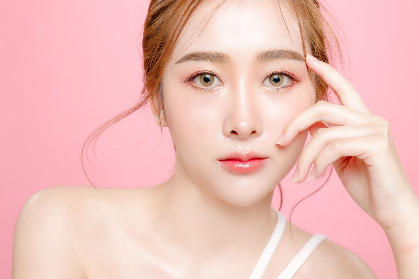 Portret kobiety na różowym tle podkreślający efekt koreańskich ust.