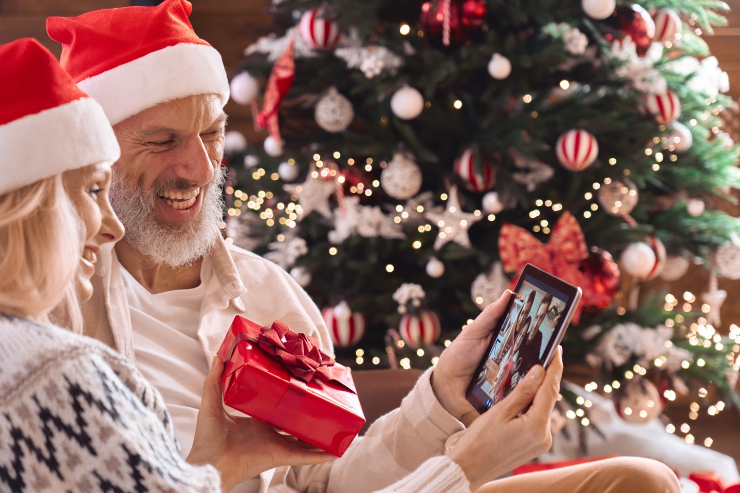 Para rodziców pokazuje świąteczny prezent na videorozmowie z rodziną