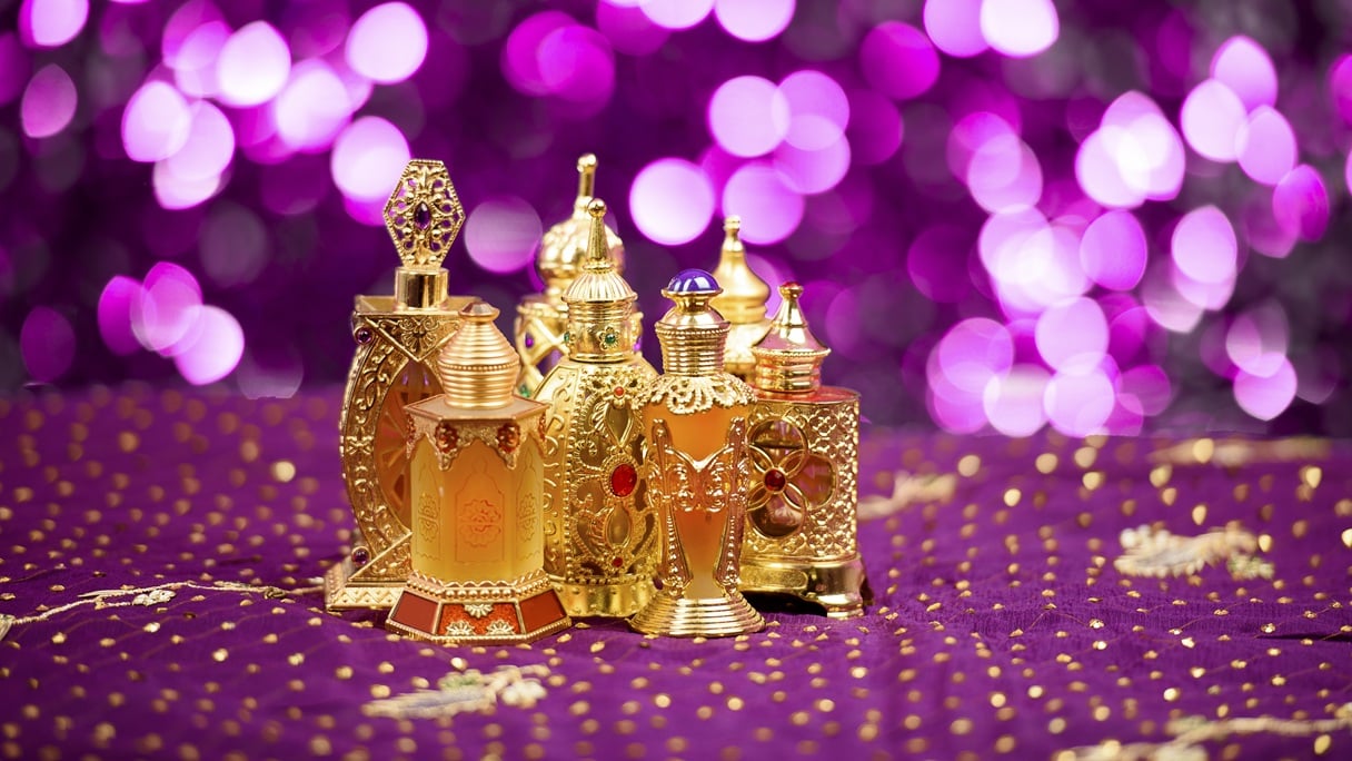 Ozdobne flakony perfum w złotych kolorach na fioletowym tle