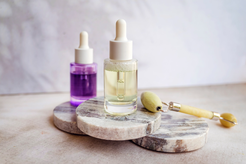 Bakuchiol i retinol na marmurowych, okrągłych deskach, a na nich roller