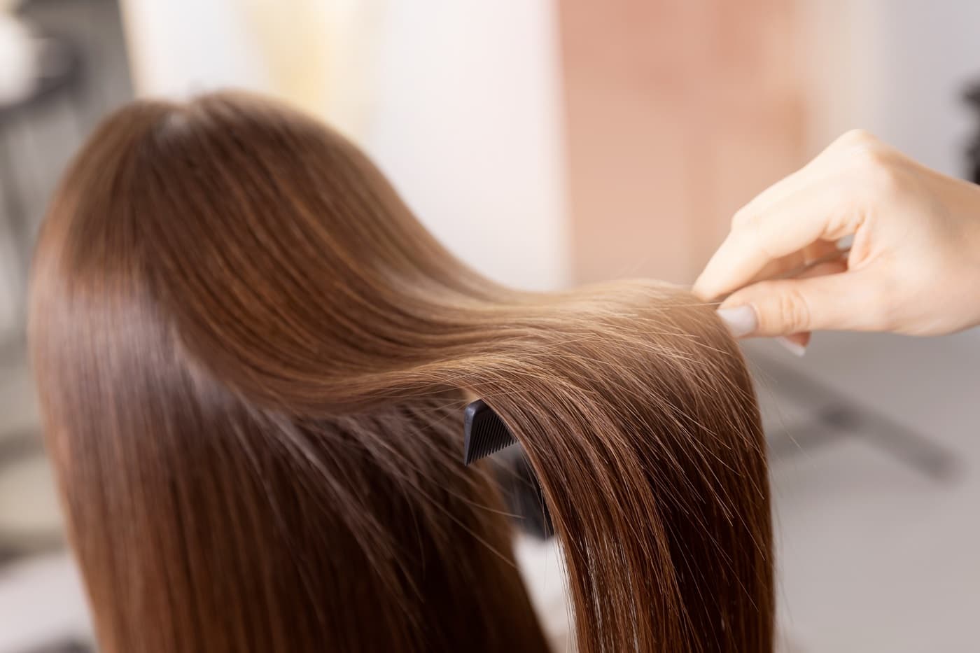 Fryzjer eksponuje włosy klientki, eksponując ich dobrą kondycję po koloryzacji