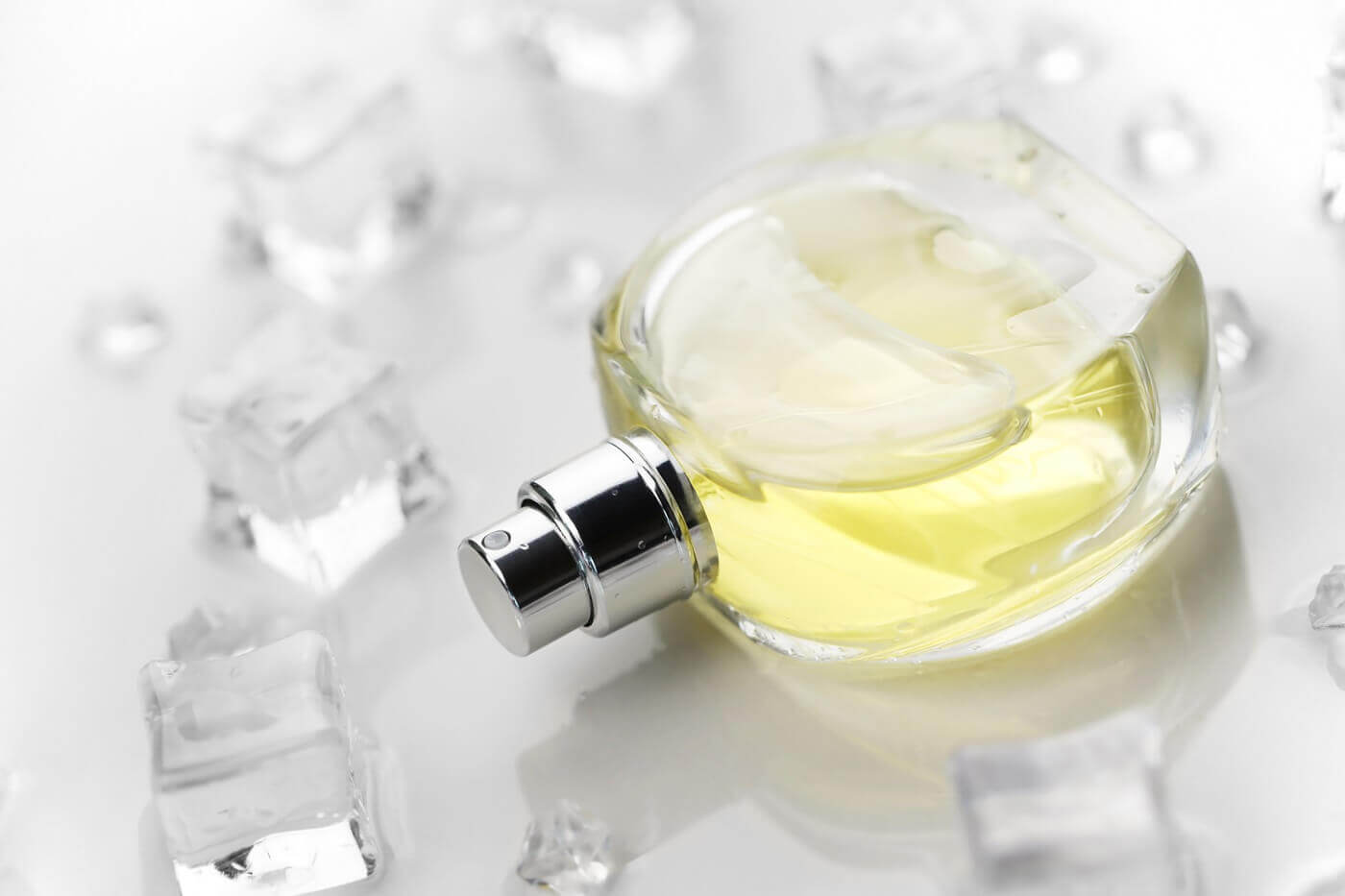 Szyprowy zapach w przezroczystym flakonie na szarym tle a wokół przezroczyste kwadratowe galaretki.