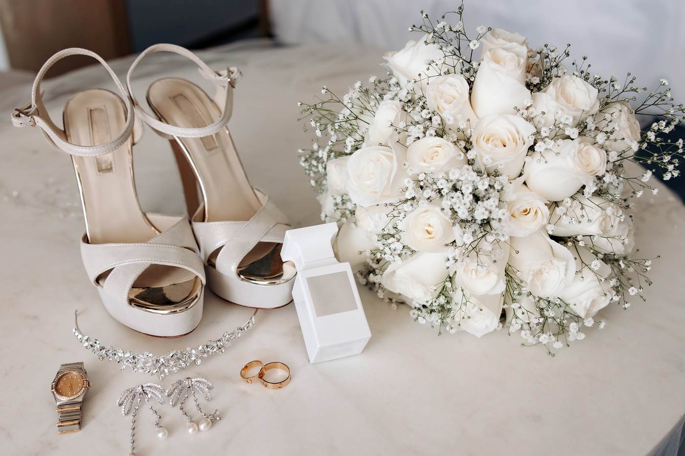Biały flakon perfum w otoczeniu akcesoriów ślubnych