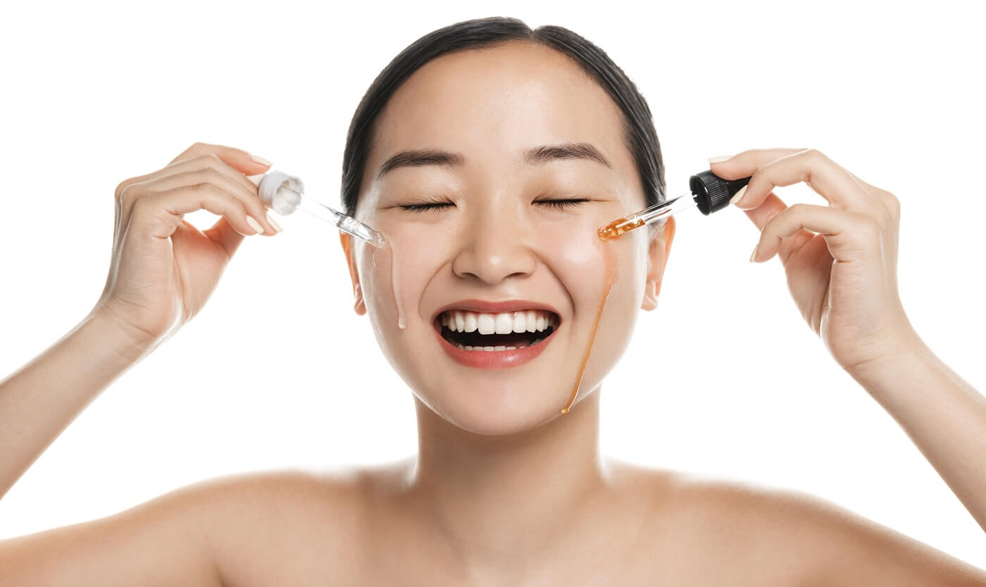 Młoda, uśmiechnięta kobieta testuje koreańskie serum do twarzy.