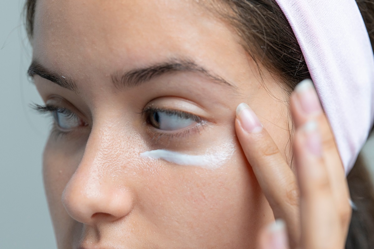 Kobieta nakłada krem na cienie pod oczami