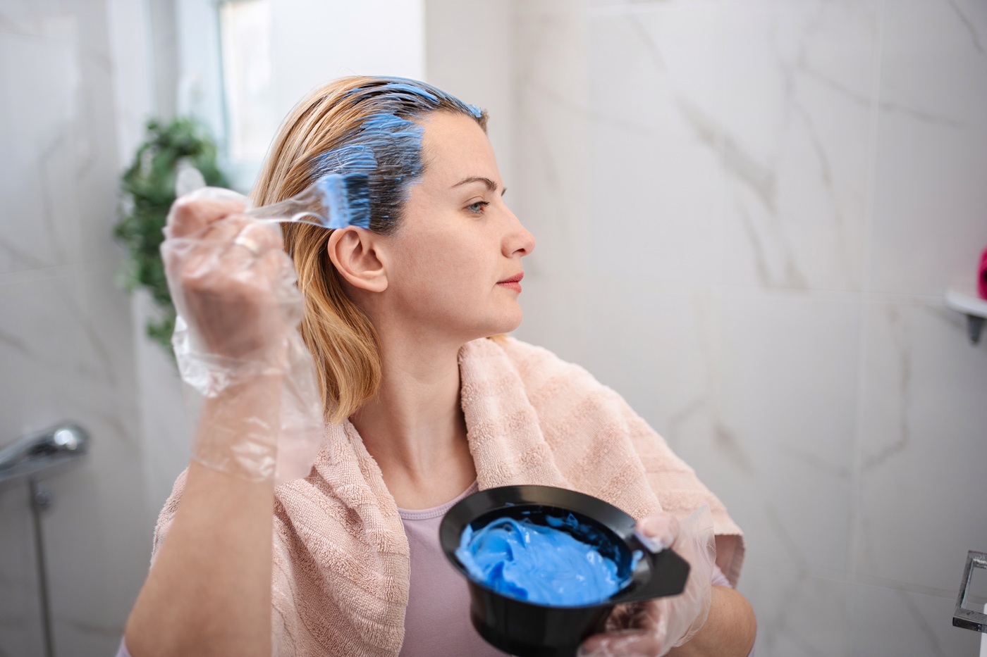 Młoda kobieta nakłada farbę na włosy w łazience.