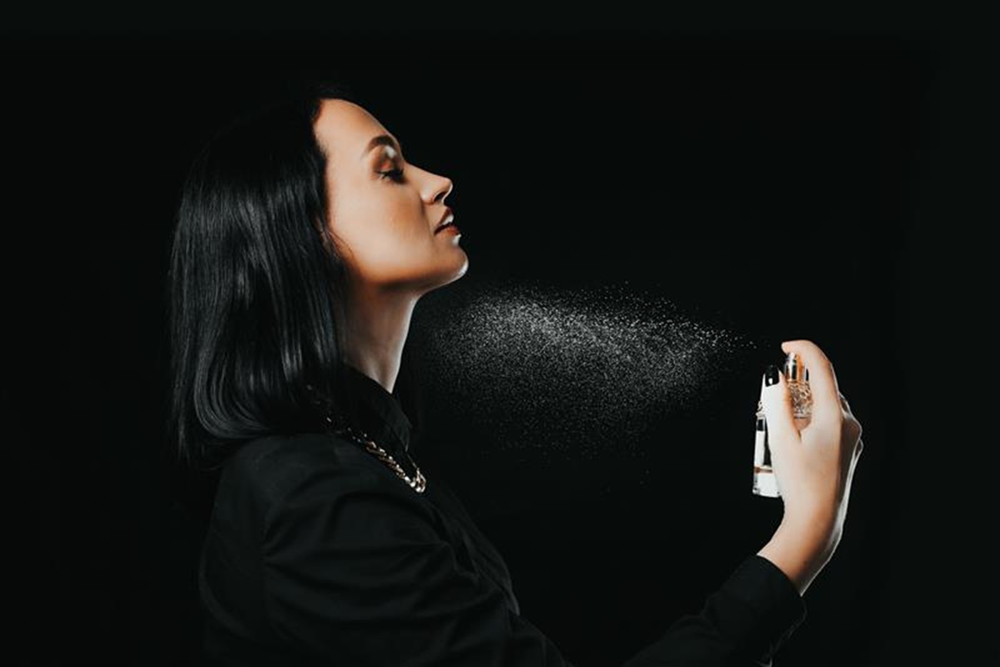 Kobieta w szlafroku aplikuje perfumy na szyję