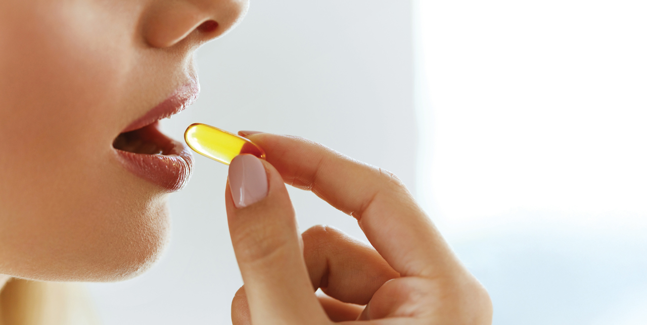 Kobieta zażywająca kapsułkę z kwasem omega-3