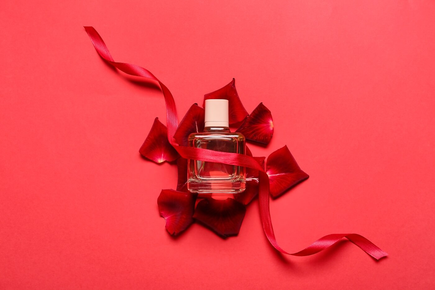 Uwodzicielskie perfumy na czerwonym tle przewiązane wstążką