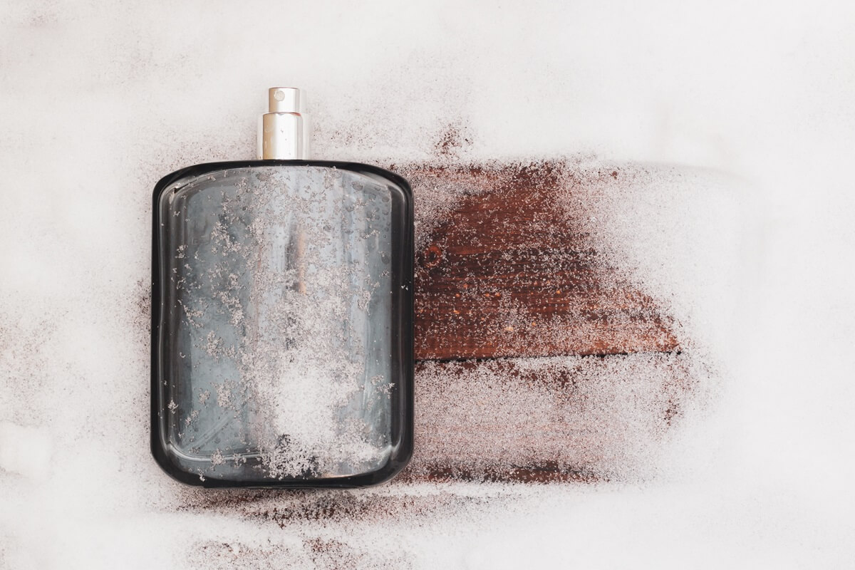 Męski flakon perfum na zimę na ławce przysypanej śniegiem.