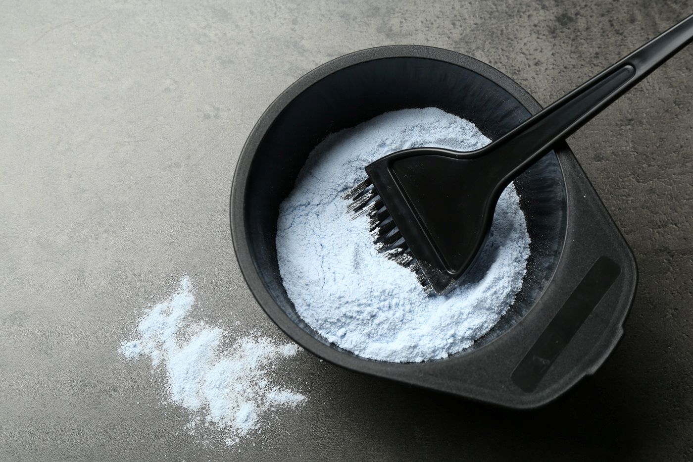 Czarna miseczka z białym proszkiem do rozrabiania farby i pędzelkiem do mieszania.