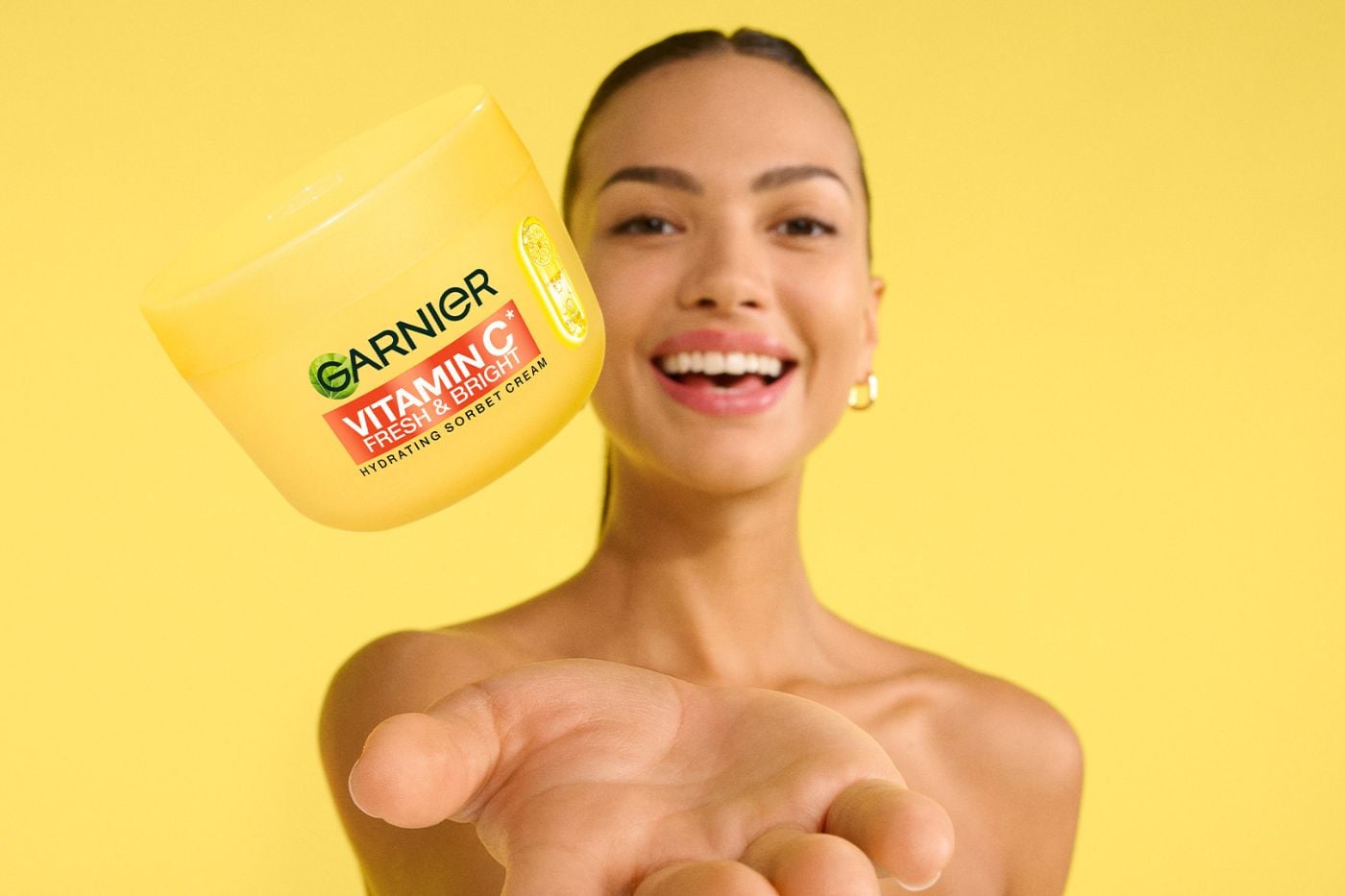 Kobieta podrzucająca krem-sorbet Vitamin C Fresh & Bright od Garnier.