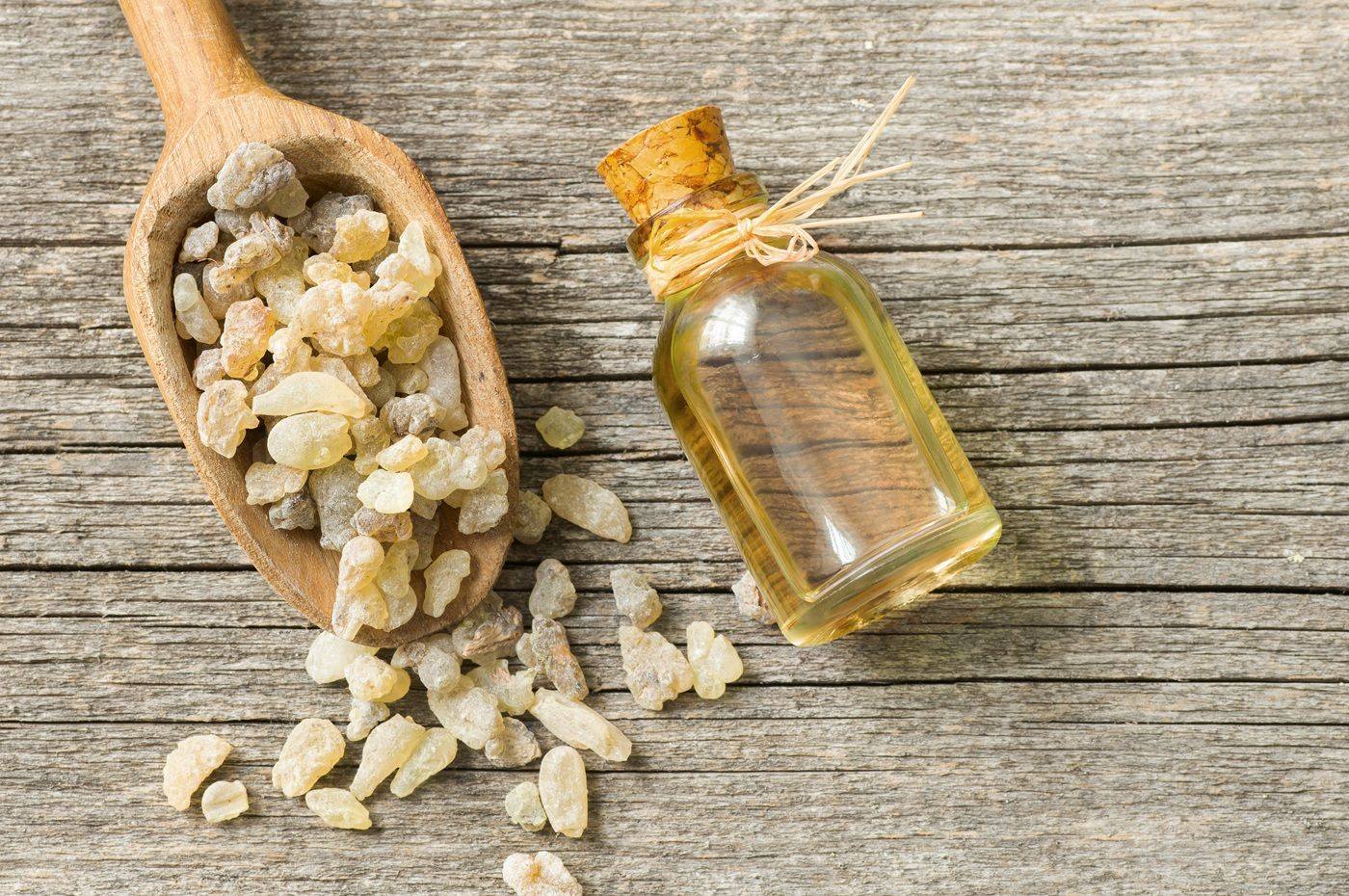 Buteleczka z olejkiem zapachowych leży obok drewnianej łyżki z żywicą