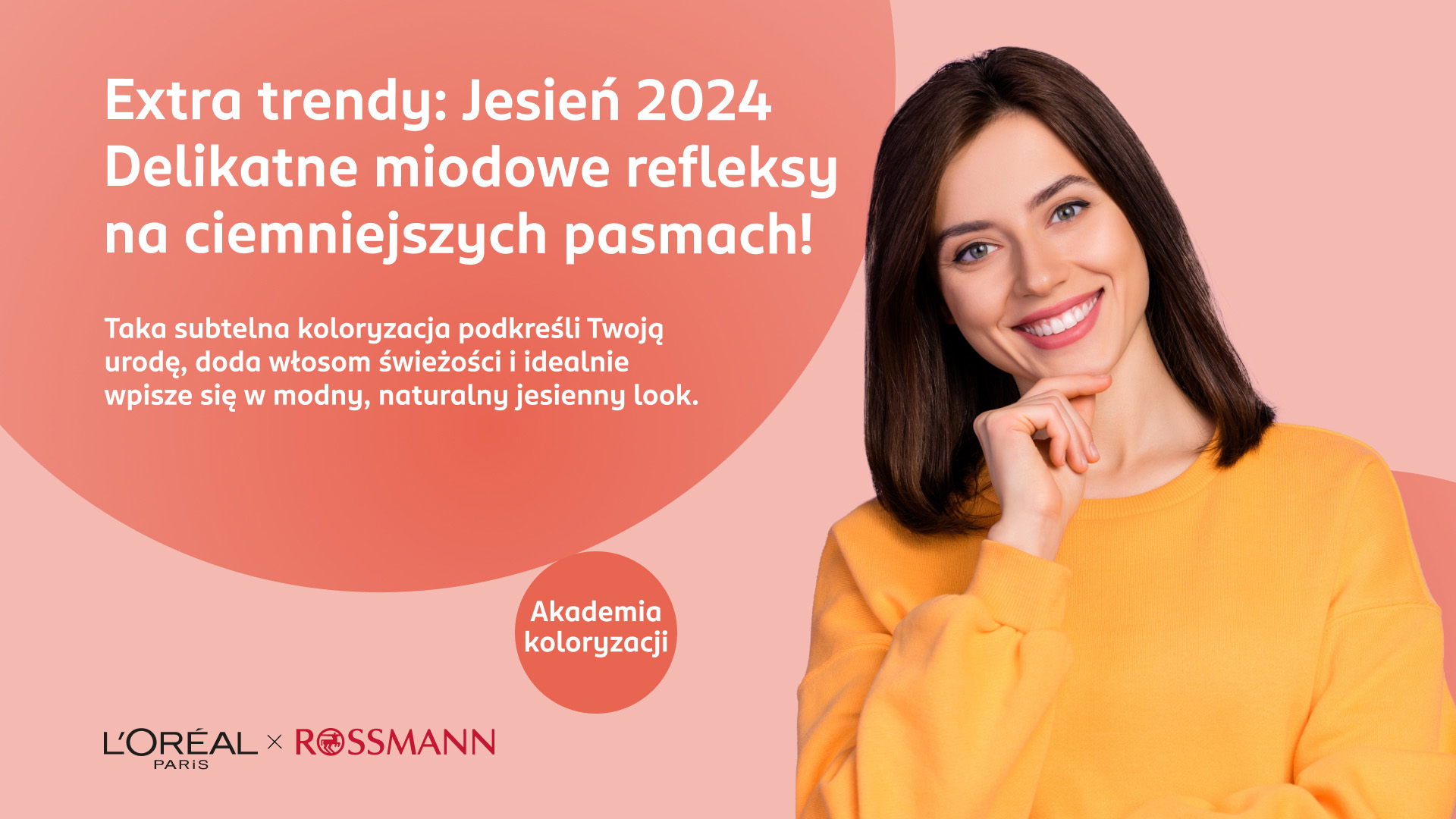 Uśmiechnięta kobieta z brązowymi włosami i w żółtym swetrze trzyma się za brodę.