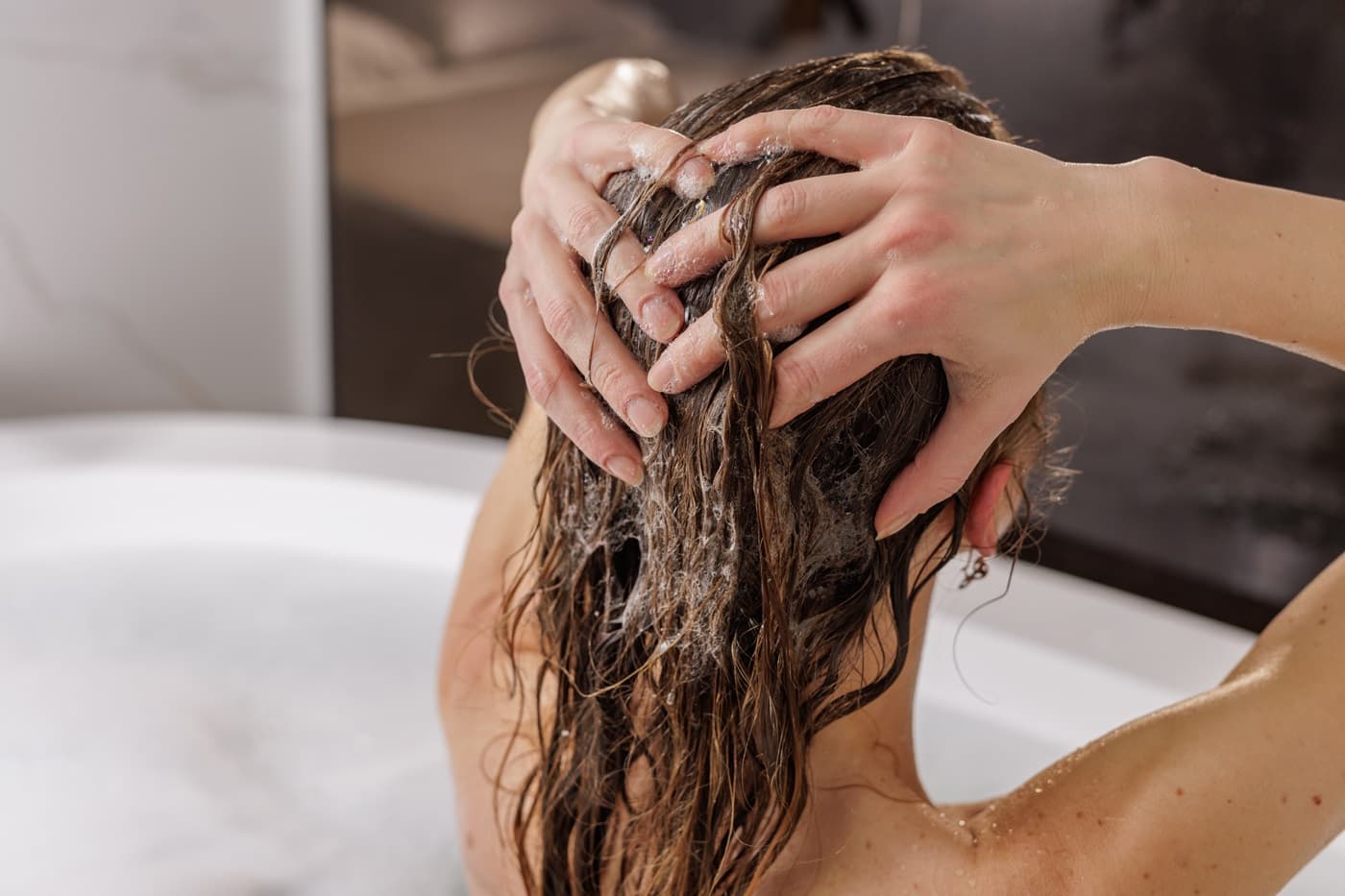 Kobieta w wannie myje włosy przed farbowaniem włosów.