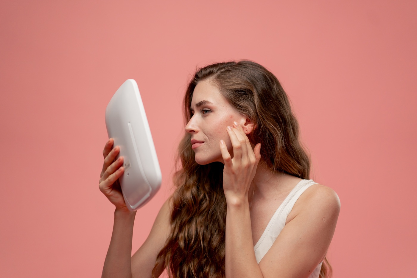 Kobieta ogląda cerę w lustrze i dotyka policzka z niedoskonałościami