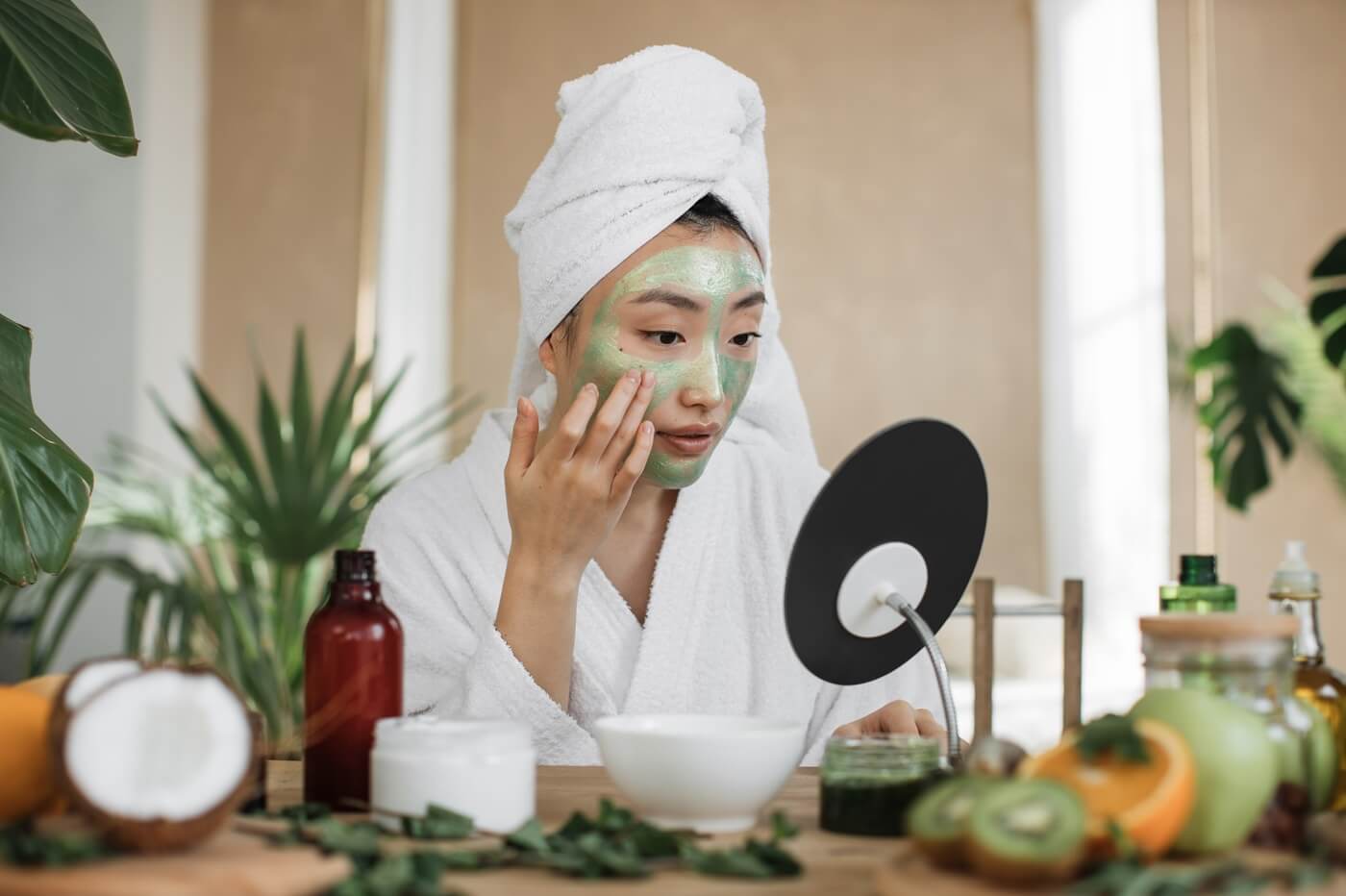 Kobieta podczas domowe spa w zielonej maseczce, przegląda się w lustrze i stosuje koreańską pielęgnację