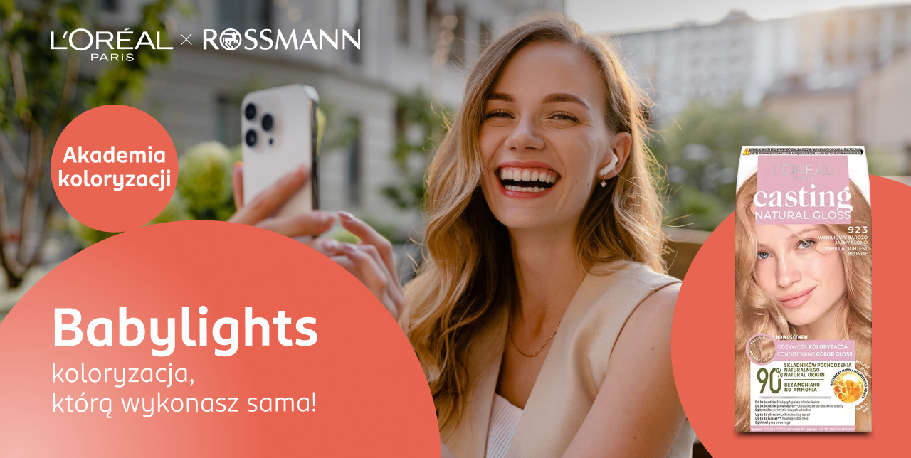  Uśmiechnięta młoda kobieta trzyma telefon i patrzy przed siebie.