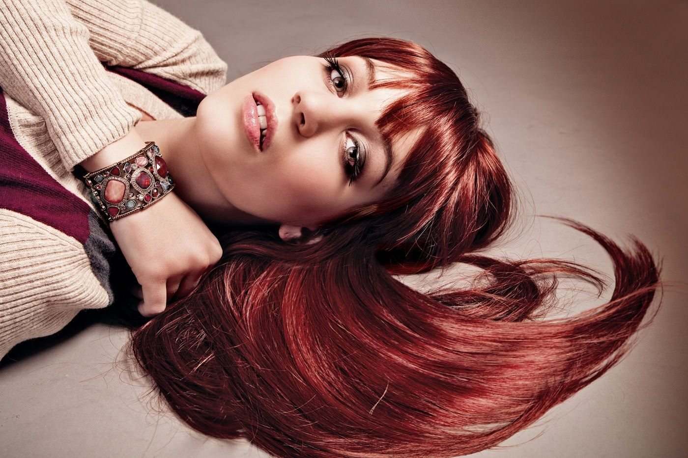 Zbliżenie na kobietę leżącą na boku, z długimi, intensywnie rudymi włosami rozłożonymi wokół głowy.