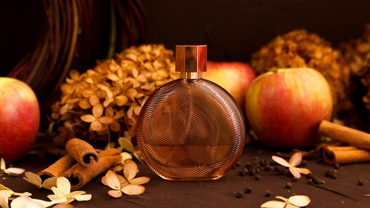 Flakon perfum w jesiennej aranżacji z jabłkami i cynamonem