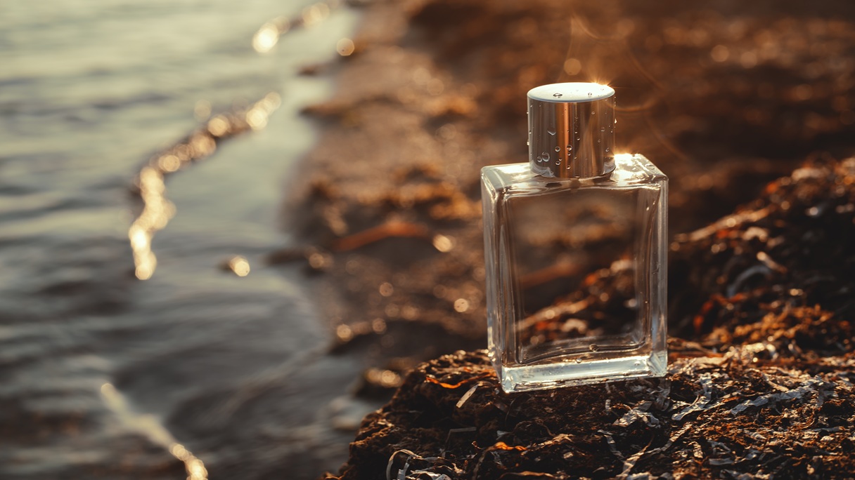 Flakon perfum na brzegu morza w ciepłym świetle zachodzącego słońca