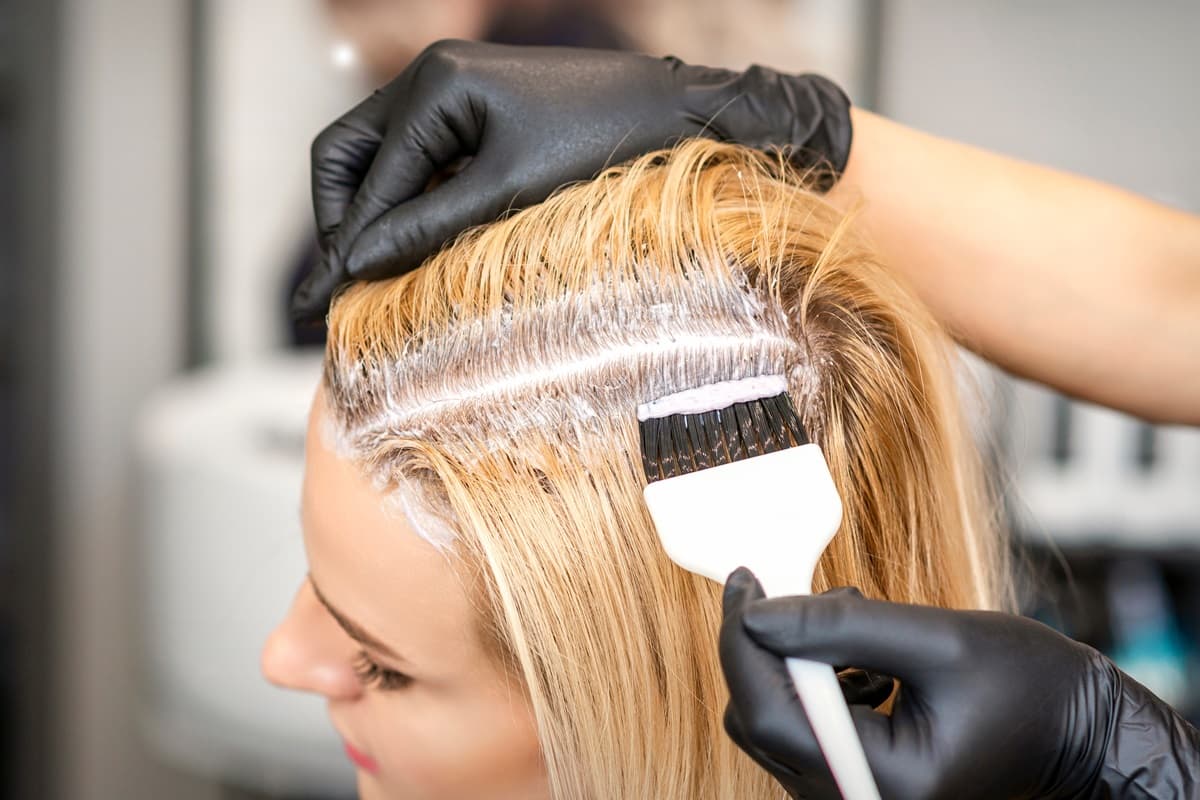 Kobieta podczas farbowania odrostów u fryzjera.